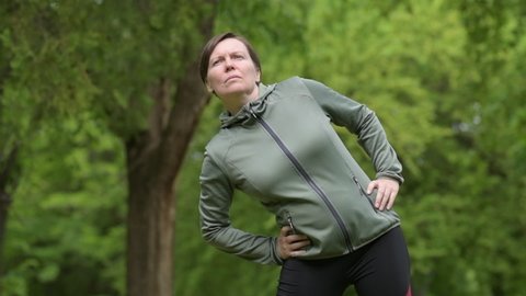 Portrait of adult female jogger stretching and warming up in park ready for running on the track, healthy lifestyle and recreational activity in 40s