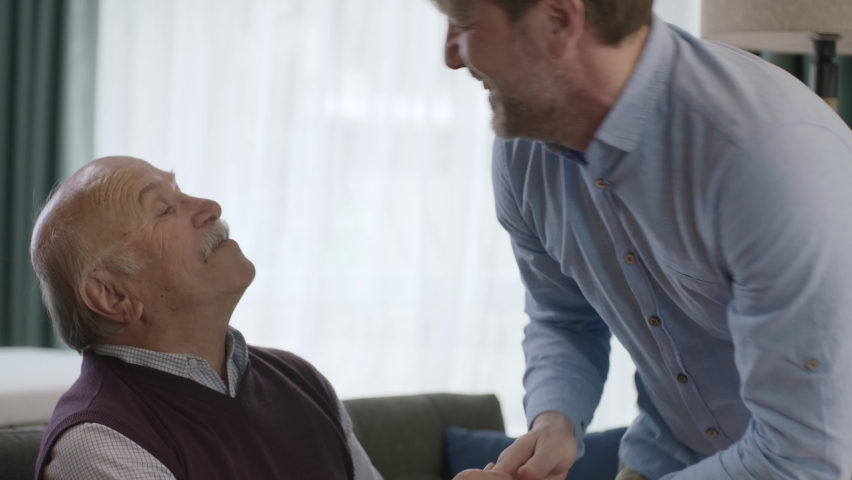 The young man is happy to see his father come to visit. The old man and his son are smiling happily at the camera. Portrait of happy father and son. Royalty-Free Stock Footage #1089714657