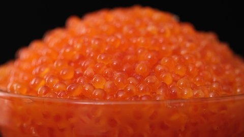 Red caviar. Bowls with red salmon salted roe caviar on tasting table. Expensive healthy food concept isolated on black background close-up slow motion rotating, spin, rotate