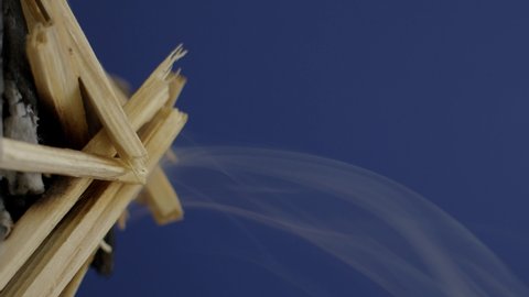 Close-up smoke of a burning wood, transparent and natural wood ash on a blue background. Slow motion, 4K.