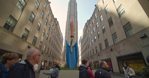New York, New York United States - April 23,  2022: Earth day Display in front of Rockefeller Center. Giant Garden hand shovel. People walk on 5th ave.