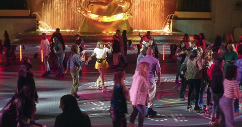 New York, New York United States - April 23,  2022: Diverse people dancing and roller skating at Flippers Roller Boogie Palace at the Rink in Rockefeller Center. Nighttime under the lights.