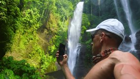 Active lifestyle people travel in tropical rainforest jungle and making video on phone scenery waterfall on nature background 4K