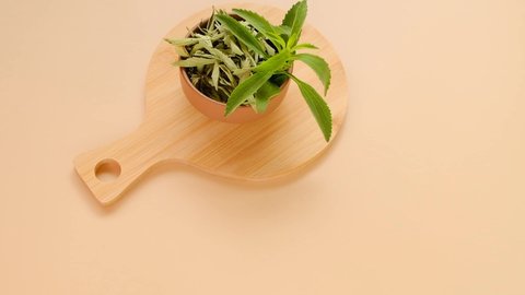 stevia leaves in round bowls with dry stevia on a round wooden board on a beige background.View from above.Organic natural sweetener.Stevia plant.