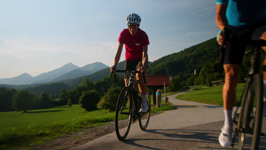Front view of a Caucasian racing bicyclist couple during intensive training along a paved road in the mountain landscape. Royalty-Free Stock Footage #1089728141