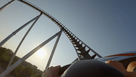 First person view riding a roller coaster in an amusement park 