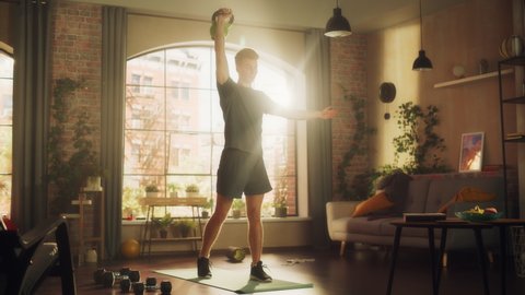 Strong Athletic Fit Young Man Lifting a Heavy Kettlebell, Doing Core Strengthening Exercises During Morning Workout at Home in Sunny Apartment. Concept of Health and Fitness.