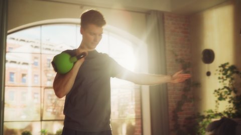 Strong Athletic Fit Young Man Lifting a Heavy Kettlebell, Doing Core Strengthening Exercises During Morning Workout at Home in Sunny Apartment. Concept of Health and Fitness. Zoom In Shot.