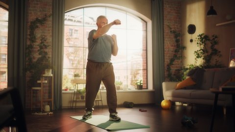 Strong Athletic Fit Middle Aged Man Doing Cardio High Knees and Core Strengthening Exercises During Morning Workout at Home in Sunny Apartment. Fitness and Recreation Concept.