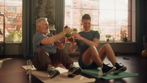 Middle Aged Man Exercising at Home with Personal Trainer. Senior Male Strengthening Core Muscles with Kettlebell Workout. Young Man or Grandchild Supporting and Training with Elderly Man.