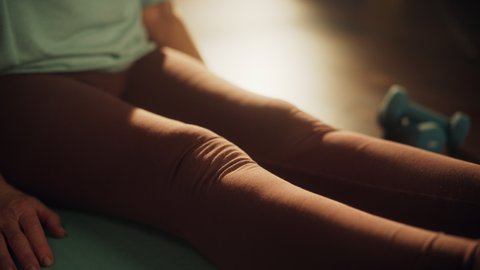 Close Up of a Senior Woman Feeling Uncomfortable Knee Pain During Morning Workout, While Exercising on a Yoga Mat at Home. Middle Aged Female Massaging Her Leg to Ease the Pain.