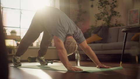 Strong Athletic Fit Middle Aged Man Training on a Yoga Mat, Doing Back Stretching and Core Strengthening Exercises During Morning Workout at Home in Sunny Apartment. Concept of Health and Fitness.