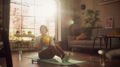 Senior Woman Exercising and Training at Home on Sunny Morning. Elderly Female Doing Crunches, Stretching Arms, Body and Muscles in Loft Apartment Living Room for Wellness and Fitness. Wide Shot.