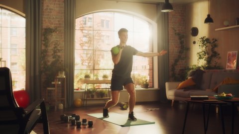Strong Athletic Fit Young Man Lifting a Heavy Kettlebell, Doing Core Strengthening Exercises During Morning Workout at Home in Sunny Apartment. Concept of Health and Fitness.