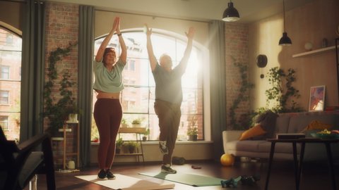 Happy Middle Aged Couple Doing Gymnastics and Yoga Stretching Exercises Together at Home on Sunny Morning. Concept of Healthy Lifestyle, Fitness, Recreation, Couple Goals, Wellbeing and Retirement.
