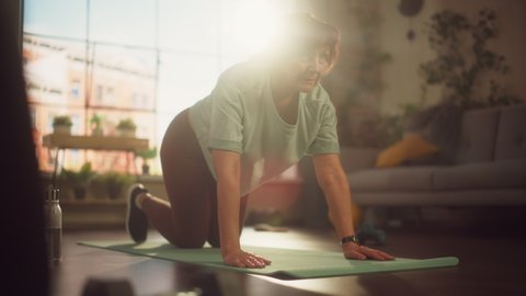 Strong Fit Middle Aged Woman Training on a Yoga Mat, Doing Stretching and Core Strengthening Exercises During Morning Workout at Home in Sunny Apartment. Health and Fitness Concept.
