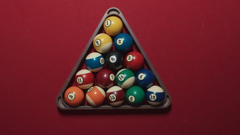 Young woman hand picking up pyramid form before pool game of 15 balls beginning on red felt table. Hobby, professional game, sport, entertainment. 15 colorful balls breaks on top view shot, 4k footage