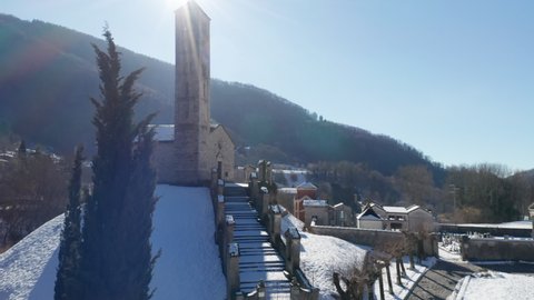 Aerial view of the small ancient church of St. Alexander in winter after a snowfall, example of the widespread Romanesque rural architecture of XII century in the Como area (Italy).