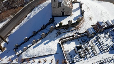 Aerial view of the small ancient church of St. Alexander in winter after a snowfall, example of the widespread Romanesque rural architecture of XII century in the Como area (Italy).