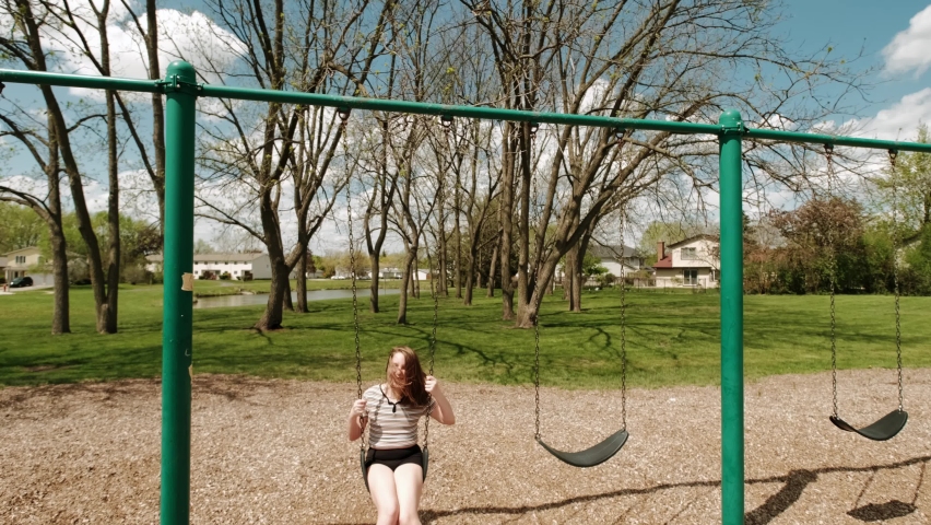 Girl on a swing and smiling happily in the park