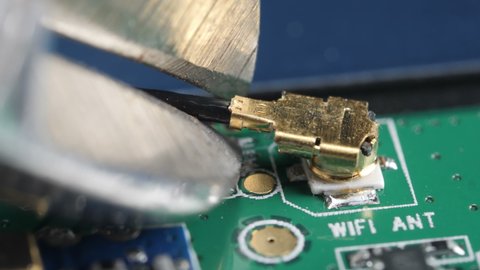 Cutting off the cable from the wifi antenna on the motherboard.
Macro video footage of removing data connection from electronic board.
