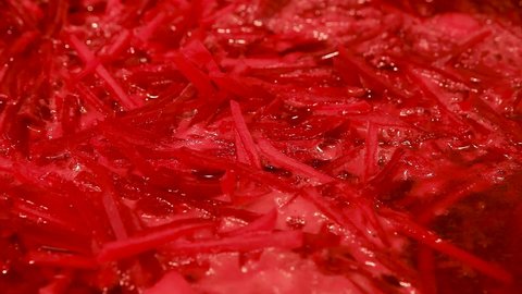 Cooking at home. Macro shot of the surface of hot borscht in a saucepan. Red beetroot soup sprinkled with finely chopped fresh dill.