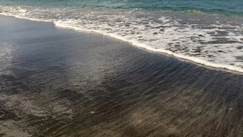 Waves on black sand beach from Nevis Peak Volcano. Pinney's Beach (Pinneys Beach) on western coast of the island of Nevis, in Saint Kitts and Nevis, Leeward Islands, West Indies in the Caribbean Sea.