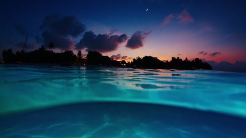 Night sea with island. Underwater splitted view of the tropical calm sea and island during late twilight