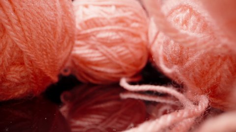 A ball of pink woolen threads, on black glass.. Dolly slider extreme close-up. Laowa Probe