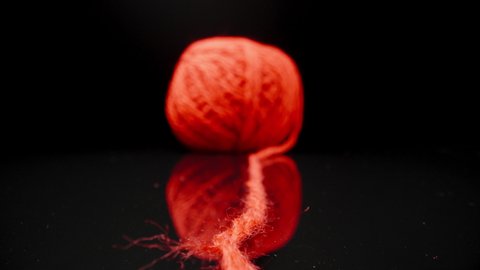 A ball of red woolen threads on black glass.. Dolly slider extreme close-up.
