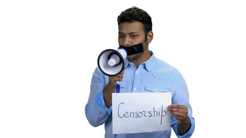 Young man with taped mouth holding megaphone. Sealed mouth man can not speak. Censorship in expression of opinion.