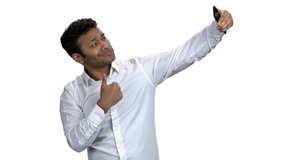 Handsome businessman taking selfie with mobile phone. Young cheerful taking picture with phone against white background. People, modern technology and fun.