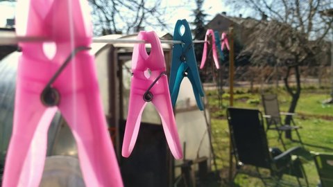 Close up of colorful pink blue clothespins hanging outside sunny day garden, static, focus on foreground, day