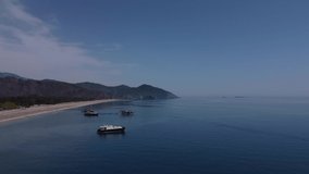 Quiet calm seascape with pleasure pirate boats along the shore, aerial view, mountain landscape and sea, drone video, sunny day. High quality 4k footage