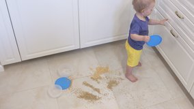 Baby exploring environment around the house, cute child playing with kitchen utensils at home opening shelf of cabinet. High quality 4k footage