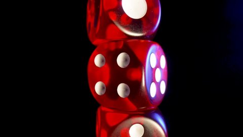 Red dice spinning on an isolated black background. Red cube, craps close up. Gambling background. The concept of playing poker, entertainment. Online casino on the Internet.