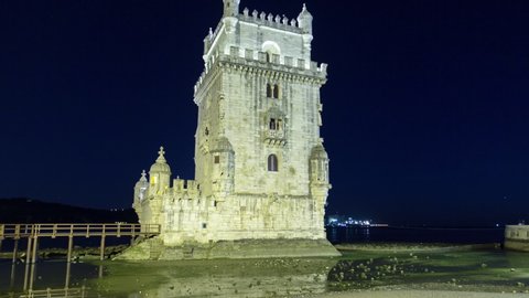 Belem Tower or Torre de Belem is a fortified tower located at the mouth of the Tagus River night timelapse hyperlapse with full Moon, lights turning on. Lisbon, Portugal