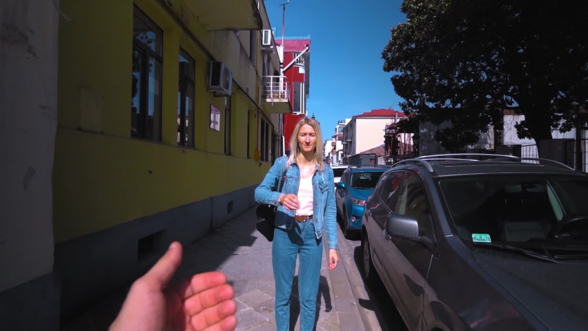 Shooting in first person, young beautiful blonde takes guy by hand and runs along street of old town on sunny day. woman in denim suit, girl. camera follows him. Travel enthusiasts. couple in love. Royalty-Free Stock Footage #1089746169