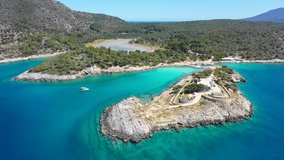 Aerial drone video of iconic Aponisos bay and lake with clear turquoise sea and pine trees,  Agistri island, Saronic gulf, Greece