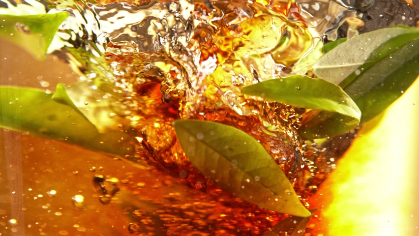 Super Slow Motion Shot of Pouring Tea into Whirl with Green Leaves at 1000fps.
