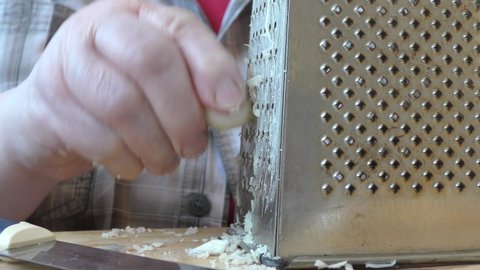 the cook rubs garlic on a grater