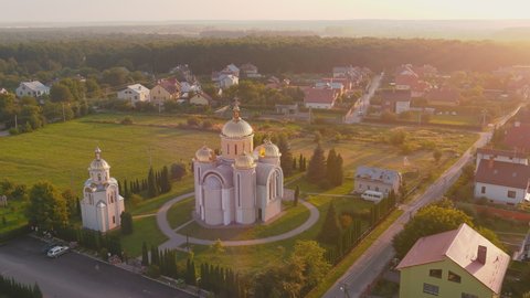 Bright Ukrainian Church in the country with golden domes and bell tower. Culture of Ukrainian spirituality and faith. panorama of a cozy village in the west of Ukraine with a large number of houses