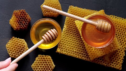 Honey dripping, pouring from a wooden spoon. Liquid fresh golden honey. Honeycombs. Healthy organic honey