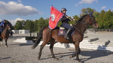 Brno, Czechia - October 08, 2021: Czech mounted police presentation, group of riders on horses carrying flags passing by, demonstration for public at defence fair