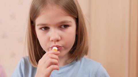 cute little girl puts balm on her lips. cosmetics for children. remedy for dry skin of the lips.