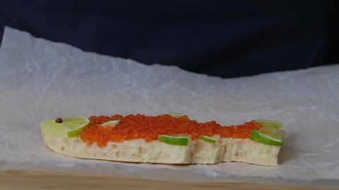 Sandwich with red caviar in shape of fish with lemon put on table. Expensive healthy food concept close-up slow motion. Sandwiches bread  toast with salmon caviar salted roe. Fish dish. Sea food