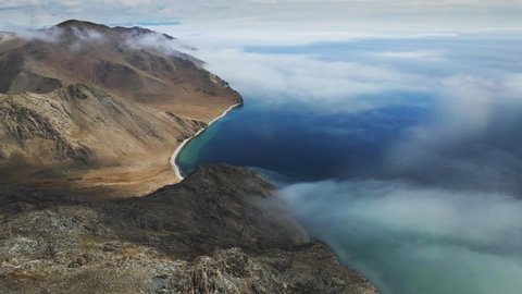 Beautiful shore of Baikal lake with clear blue water. Clouds over the lake and mountains in misty morning. Aerial drone view. Baikal lake, Siberia, Russia. Beautiful spring landscape. 
