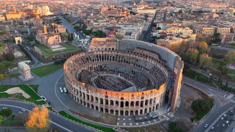 Roman Coliseum in the first rays of sun, aerial view of a famous Italian landmark in Rome, ruins of ancient Roman empire, world heritage site in Italy. High quality 4k footage