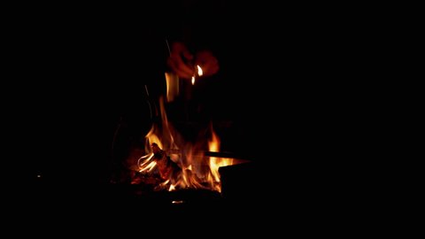Male Hands, Using of Matches, Kindles a Night CampFire in the Open Air. Hot fire, smoldering coals, sparks, smoke, ash flying up. Tourist warms himself up by the fire. Concept survival, hiking, trip.