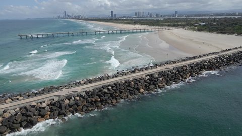 Ocean Waves On Sandy Beach Between Sand Bypass Pumping Jetty And The Spit Seawall In QLD, Australia. - aerial